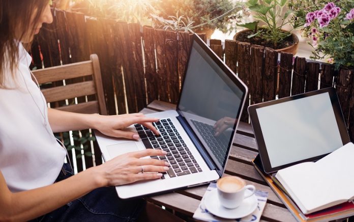 Young woman with laptop on summer balcony